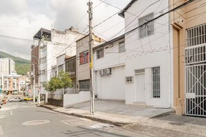 A street view with residential buildings, a visible road sign indicating a 30 km/h speed limit, and a utility pole with overhead wires. - Moon house Modern Design, Comfortable & Elegant. (Cali)