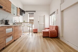Una cuina compacta amb armaris de fusta, taulell de marbre i tamborets moderns.