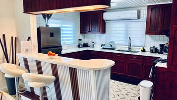 A modern kitchen with a central island, bar stools, a built-in oven, and a microwave.