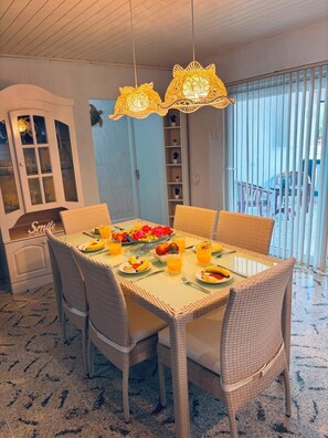 A dining area with wicker chairs, a glass-top table, and a fruit platter. - Fabulous 3-bedroom house with AC in charming Savaneta (Savaneta)