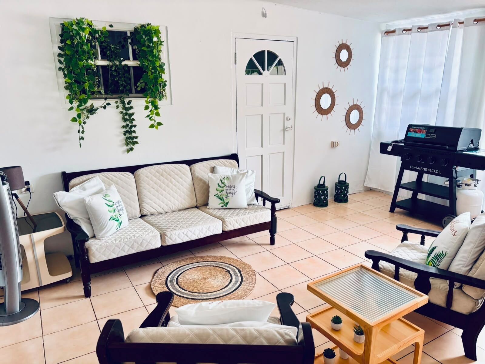 A living room with a sofa, a coffee table, a TV stand, a grill, and decorative wall art.