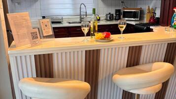 A kitchen with a bar area, two bar stools, a microwave, and a sink.