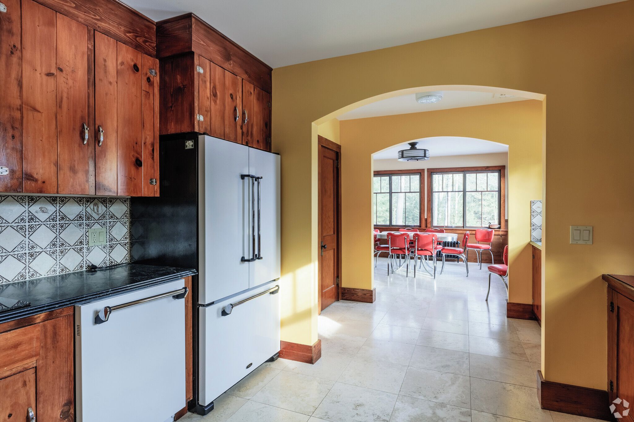 A kitchen with wooden cabinets, a white refrigerator, and a tiled backsplash.