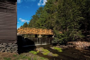 A wooden bridge over a stream with a waterfall, surrounded by dense forest. - Spacious 4-bedroom house in fabulous Sparrow Bush with AC (Sparrow Bush)