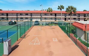 A tennis court with a net, a parking area, and a building with a red roof. - Cozy 2-bedroom condo in lovely St. Augustine across from the beach and Fun (St. Augustine)