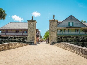 A historic street with stone walls and colonial-style buildings, including a house with a green porch and a building with a balcony. - Cozy 2-bedroom condo in lovely St. Augustine across from the beach and Fun (St. Augustine)