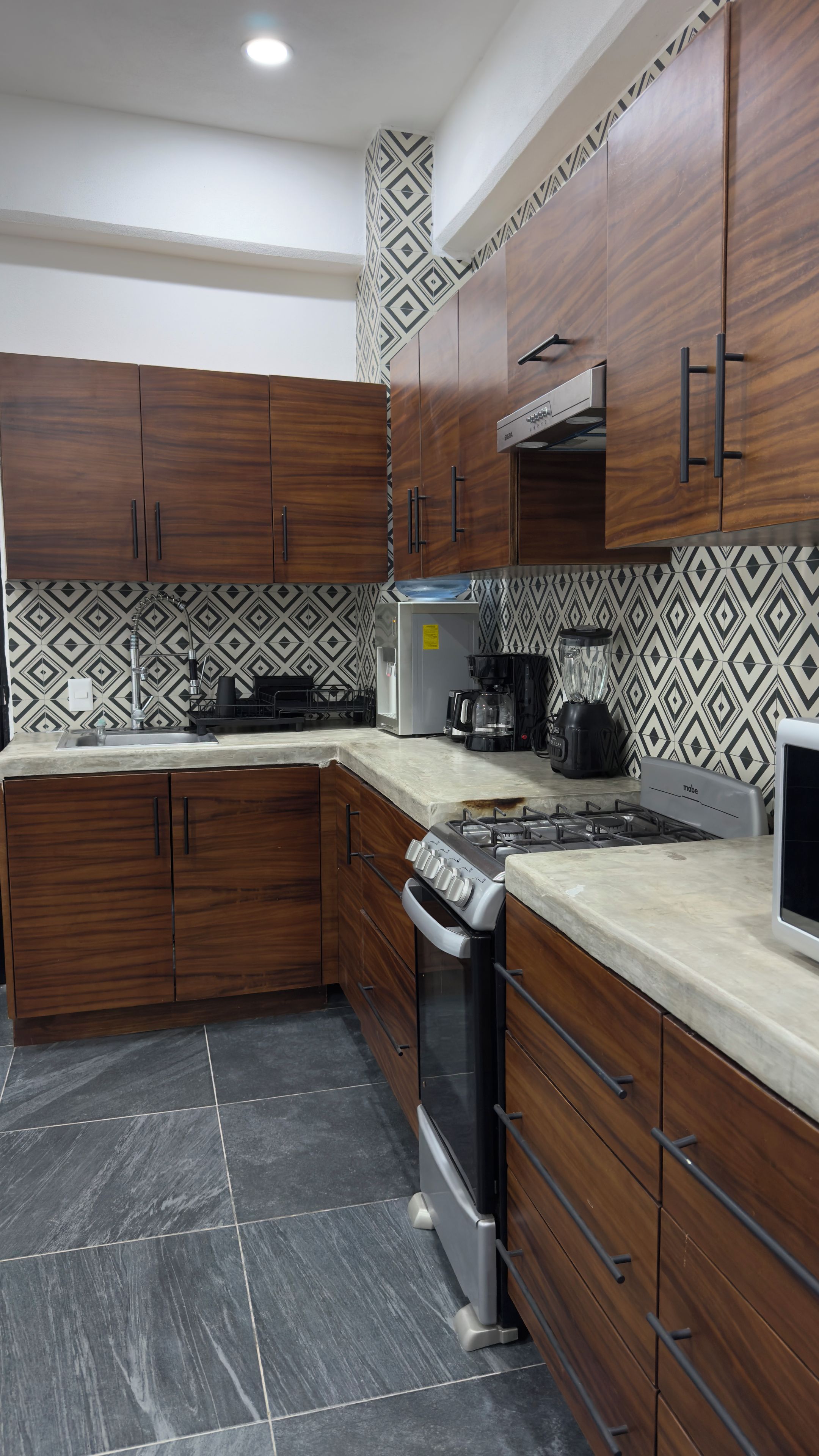 Una cocina moderna con armarios de madera oscura, una estufa de acero inoxidable y un salpicadero decorativo.