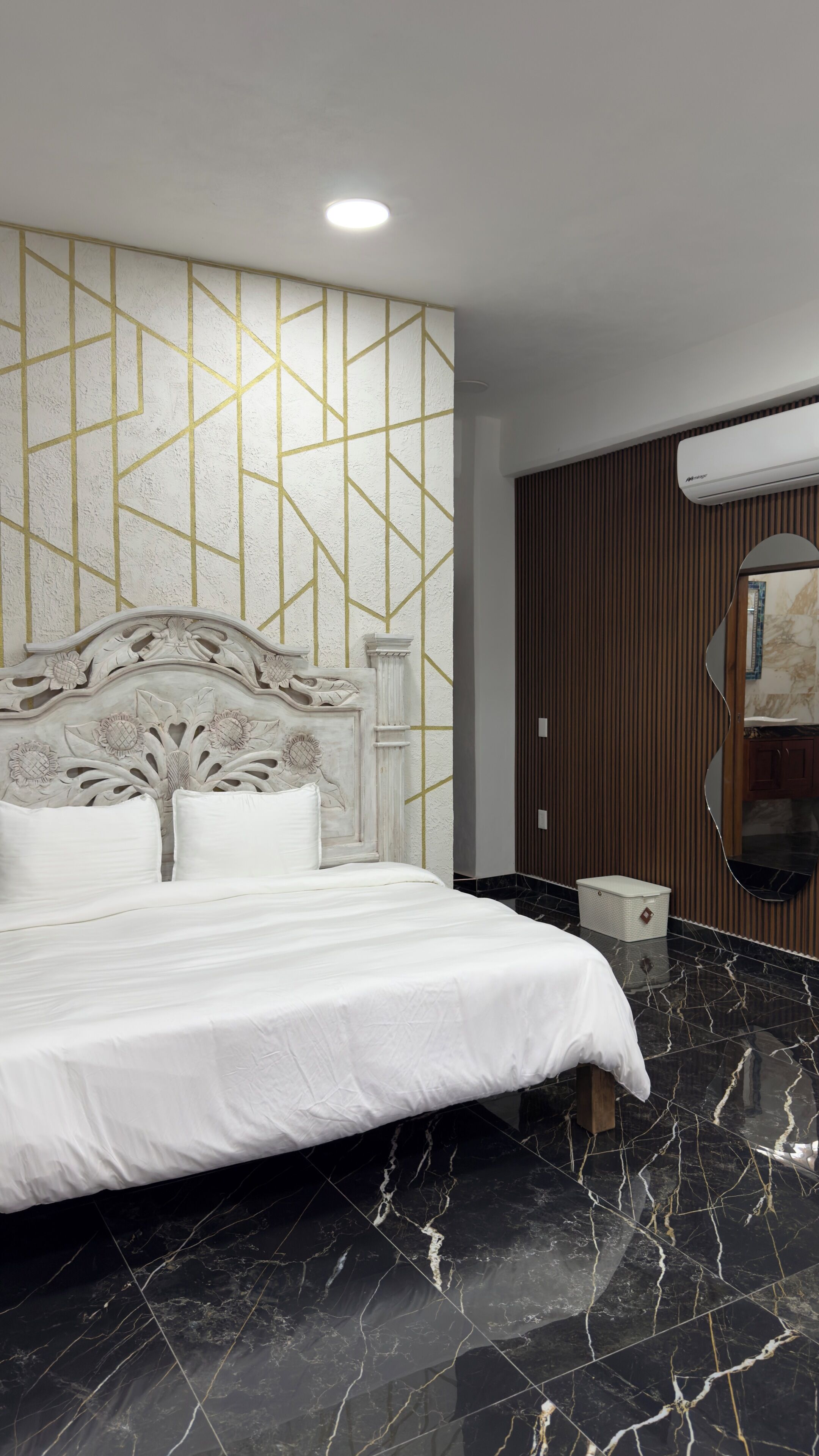 A modern bedroom with a marble floor, a white bed with a decorative headboard, and a geometric patterned wall.