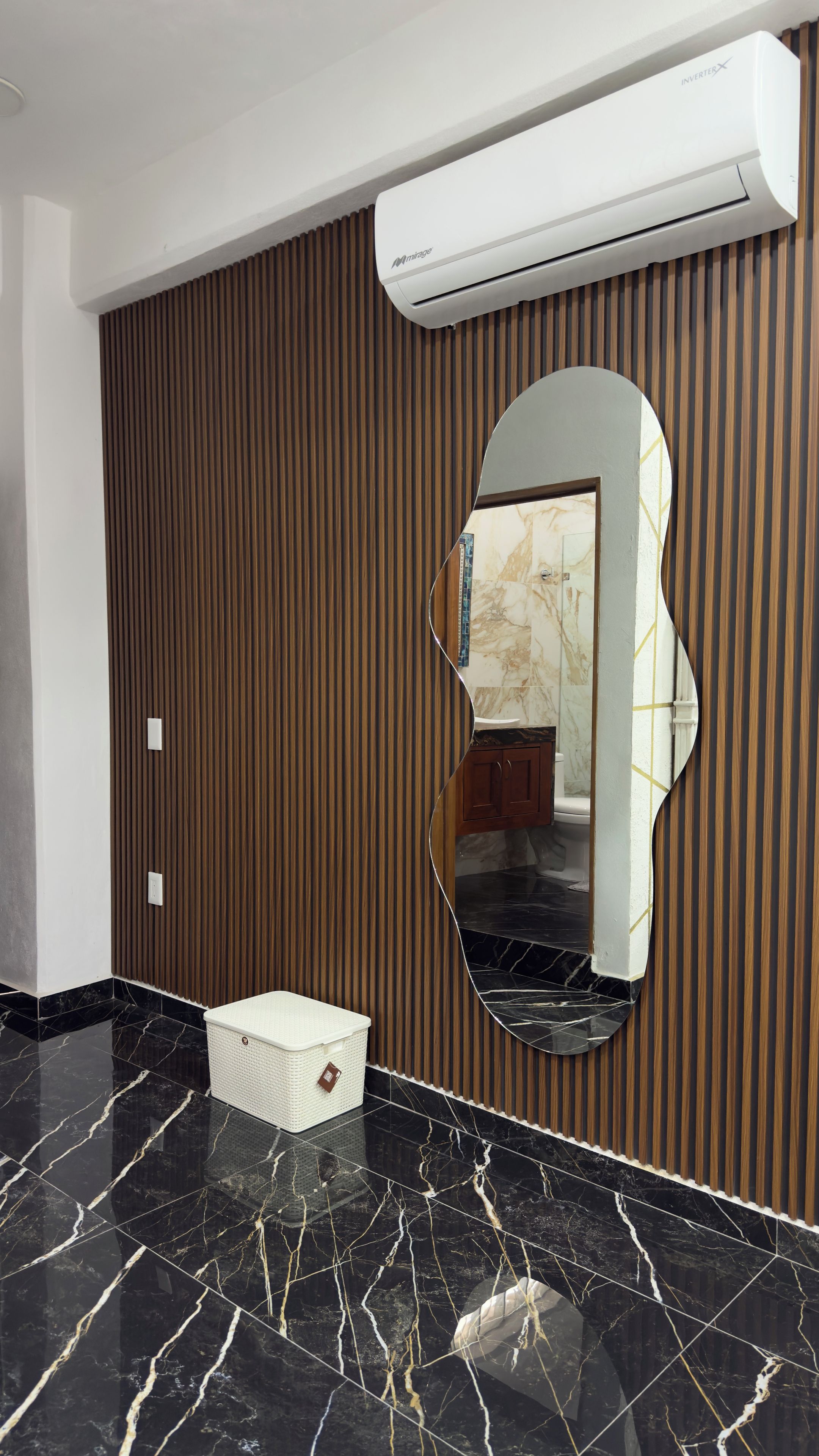 Un baño con tocador, espejo y un cesto blanco para guardar objetos.