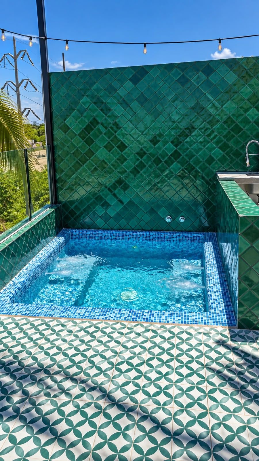 A swimming pool with a geometric tile pattern, surrounded by a green-tiled wall and a patterned floor.