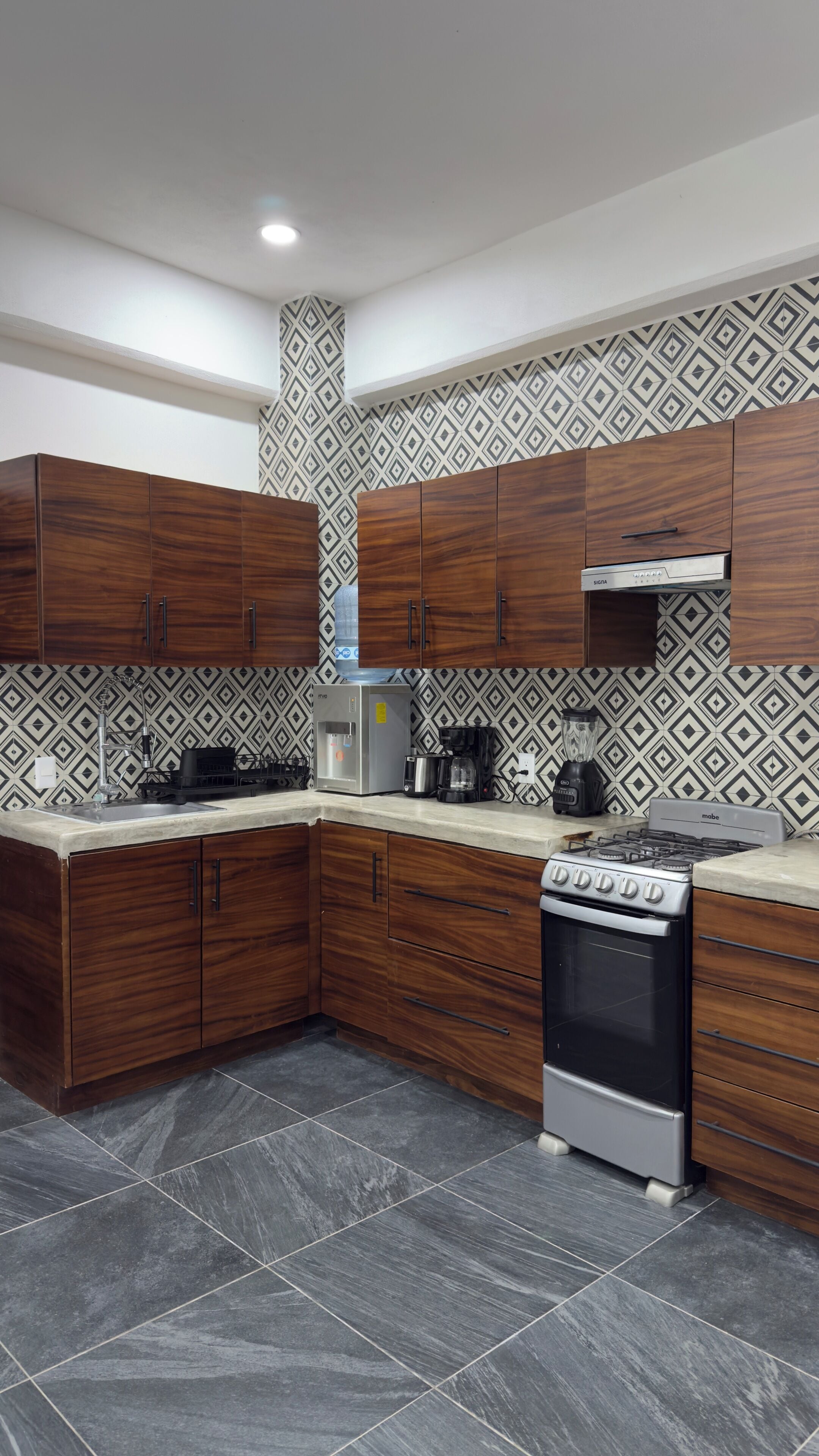 Una cocina moderna con armarios de madera oscura, estufa integrada y un salpicadero con diseño.