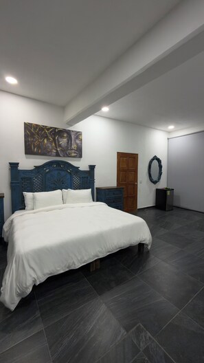 A bedroom with a large bed, a wooden door, a dresser, and a wall-mounted artwork. - Villa SoL Boutique Hotel Puerto Vallarta (Puerto Vallarta)