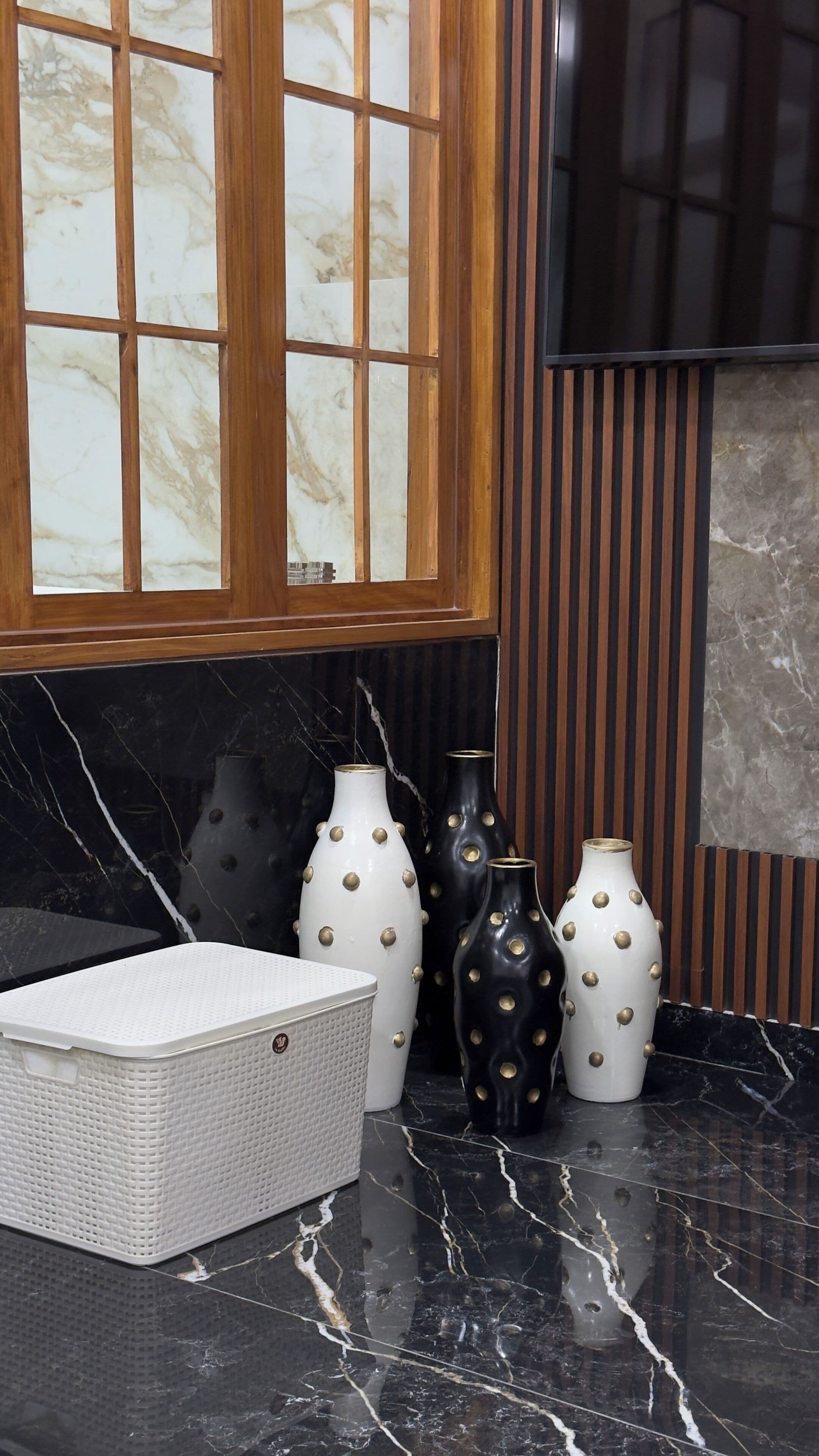 A kitchen with a marble countertop, a white basket, and decorative vases with gold accents.
