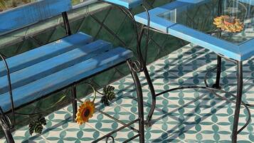 A blue bench and a glass table with a flower on a patterned floor.