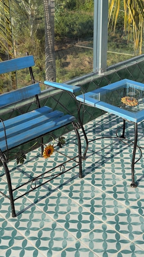 Un banco azul y una mesa de vidrio con una flor sobre un suelo estampado.