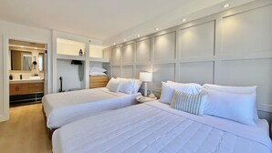 Ein Hotelzimmer mit zwei Betten, einem Badezimmer inklusive Spiegel und einem Kleiderschrank.