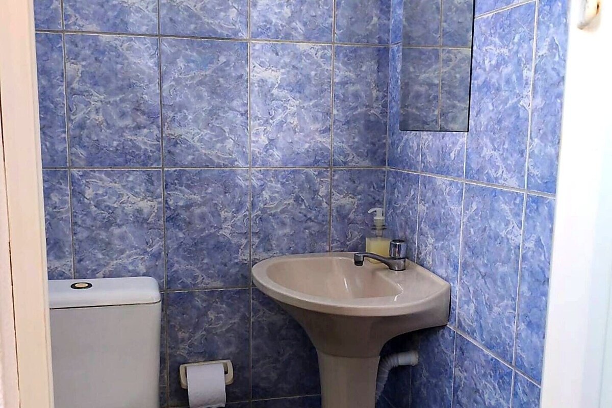 Et badeværelse med toilet, håndvask og spejl på væggen.
