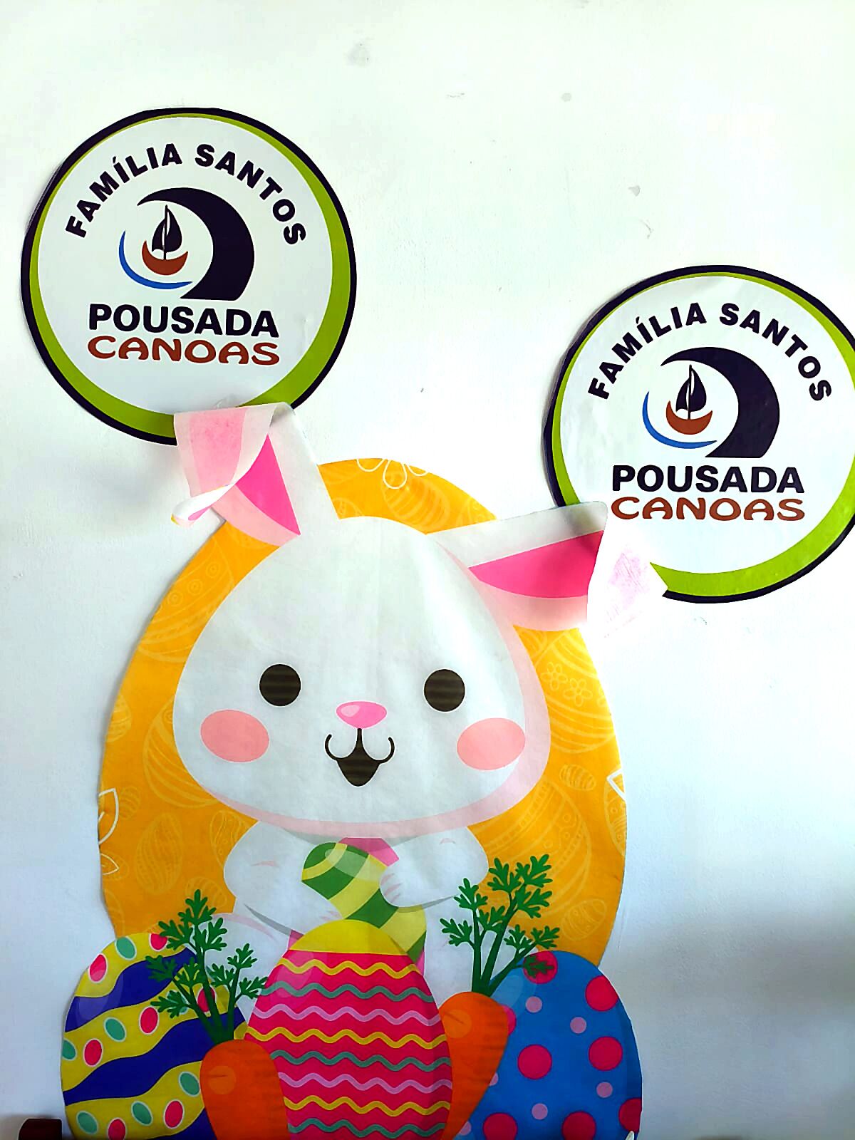 Un joli bricolage représentant un lapin de Pâques aux couleurs vives, avec un logo au-dessus.