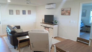 Un saló modern amb un sofà, una butaca reclinable, un televisor i una taula de dinar.