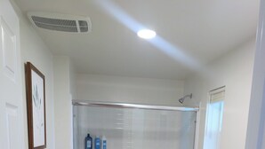 Un bany modern amb dutxa de vidre, un vàter i un lavabo amb taulell blanc.