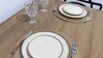 Una mesa de comedor dispuesta con platos, cubiertos y vasos.