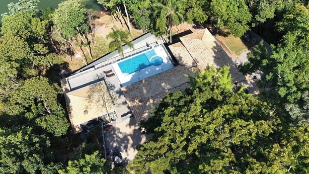 Eine Luftaufnahme eines Anwesens mit Swimmingpool, umgeben von üppiger Vegetation und blauem Himmel.
