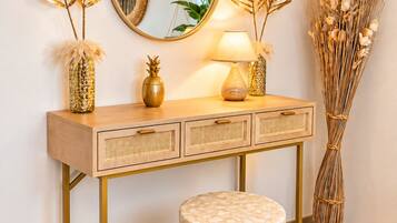 A wooden vanity with a round mirror, a lamp, and decorative items including a pineapple and dried plants.