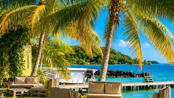 A tropical resort with palm trees, a pool, and outdoor seating.