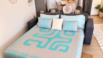 A modern bedroom with a bed, bedside tables, a mirror, and a view of the dining area.