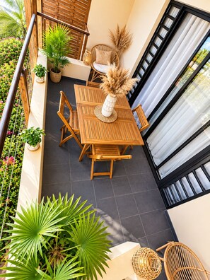 A balcony with a wooden table and chairs, surrounded by potted plants and a wicker chair. - Bora Bora Sweet Dream: cozy and elegant accommodations with a view of the Bora Bora lagoon. (Bora-Bora)
