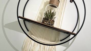 A wall-mounted macrame piece with a circular frame, a wooden shelf, and a pineapple decoration.