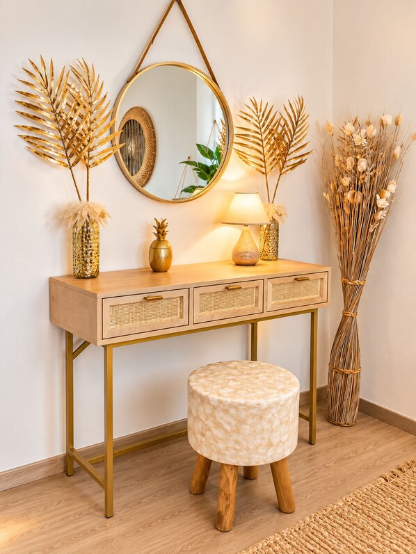 A wooden vanity with a round mirror, a lamp, and decorative items including a pineapple and dried plants.
