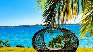 A beach scene with a woven chair and a view of the ocean.