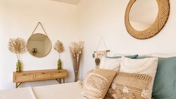 Une chambre à coucher comprenant un lit, une commode, un miroir rond et des objets de décoration.