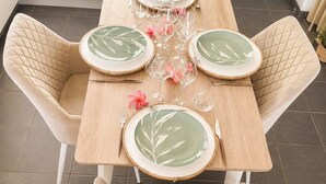 A dining table set with plates, glasses, and cutlery, surrounded by cushioned chairs.
