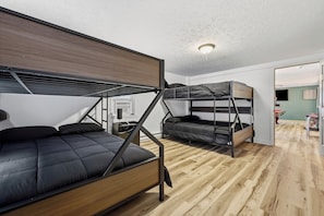 Habitación pequeña con literas, piso de madera y una lámpara en el techo.