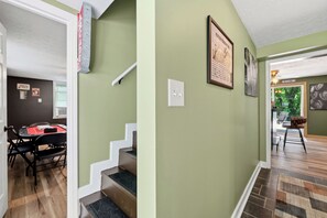 Un escalier menant à un espace repas avec une table et des chaises, un interrupteur fixé au mur et une carte encadrée accrochée au mur.