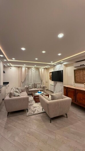 A modern living room with a sofa set, a coffee table, and a TV mounted on the wall. - Élégance à Kouba – 3 chambres, suite & garage. (Kouba)