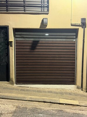 A closed garage door with a metal handle and a security camera mounted on the wall. - Élégance à Kouba – 3 chambres, suite & garage. (Kouba)