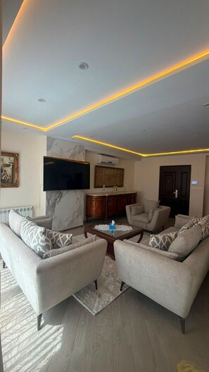 A modern living room with a flat-screen TV, marble wall, and a sofa set. - Élégance à Kouba – 3 chambres, suite & garage. (Kouba)