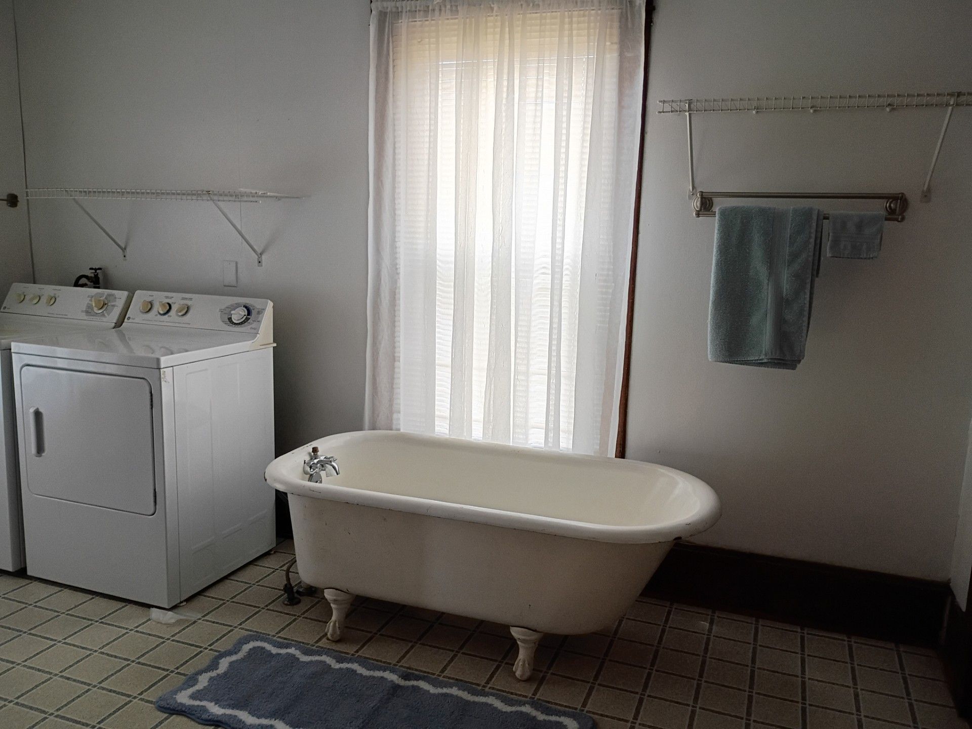 A bathroom with a white bathtub, a washing machine, and a drying rack.
