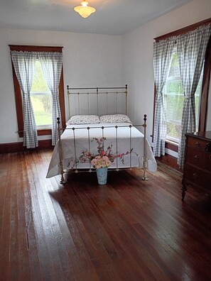 Una habitación con una cama, un aparador y un jarrón con flores.