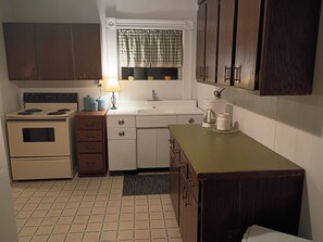 A compact kitchen with a stove, sink, and cabinets.