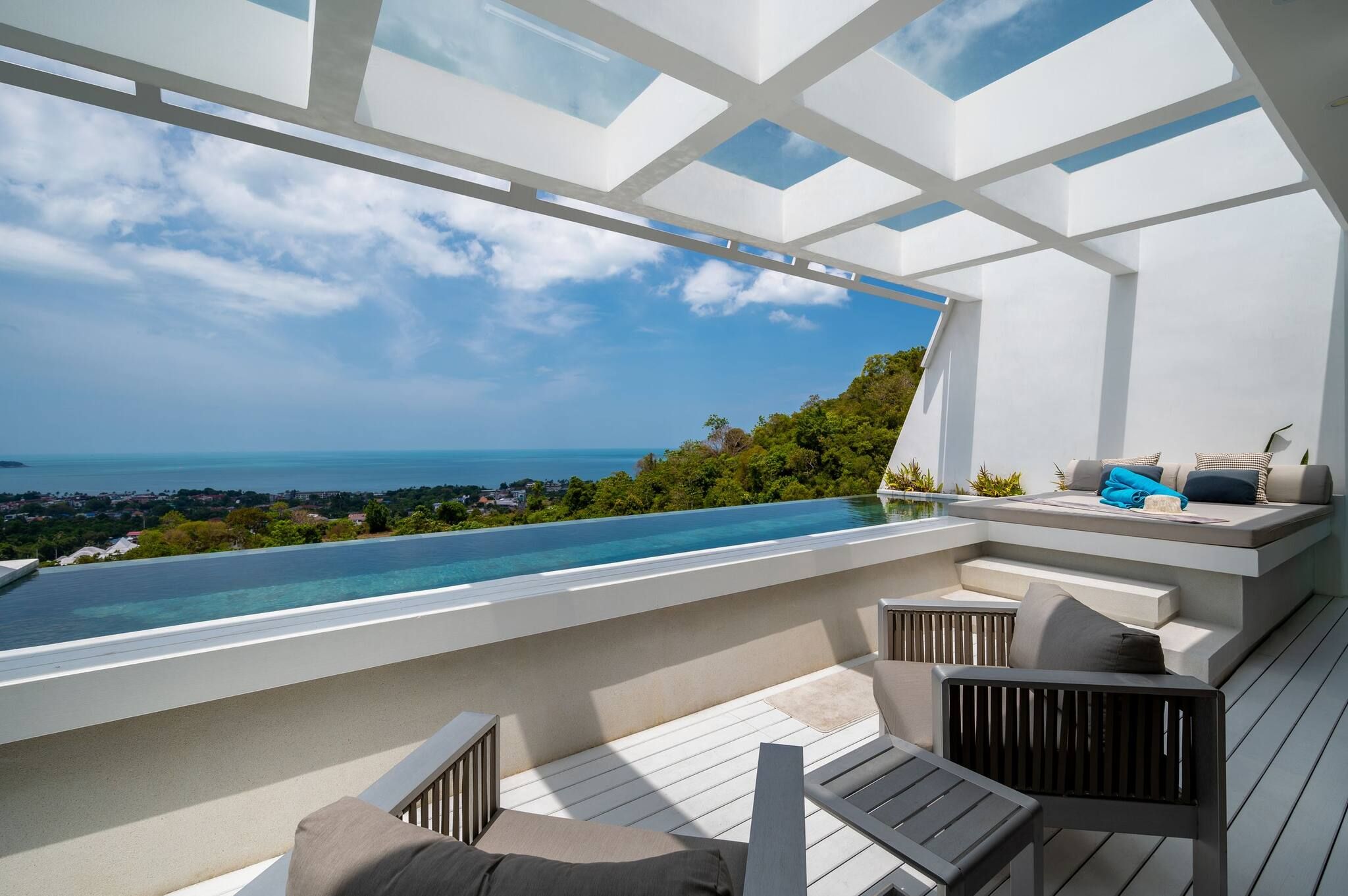 Área de estar moderna ao ar livre com piscina e vista para a paisagem costeira.