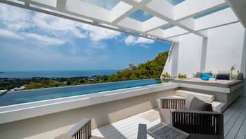 Área de estar moderna ao ar livre com piscina e vista para a paisagem costeira.