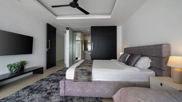 Quarto moderno com cama, mesas de cabeceira, televisão e ventoinha de teto.