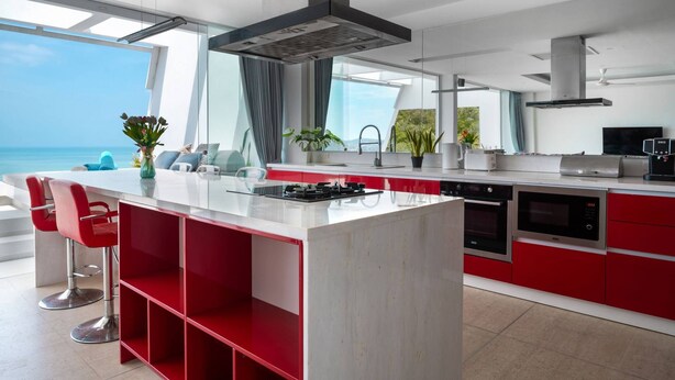 A modern kitchen with a central island, red cabinetry, and a view of the ocean. - Central Villa With Mountain & sea View (Koh Samui)
