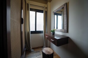 A room with a wooden vanity, a mirror, a small stool, and a window with curtains. - Chic 2-Bedroom Loft - Walk to Egyptian Museum, Tahrir Sq. & Nile (Cairo Governorate)