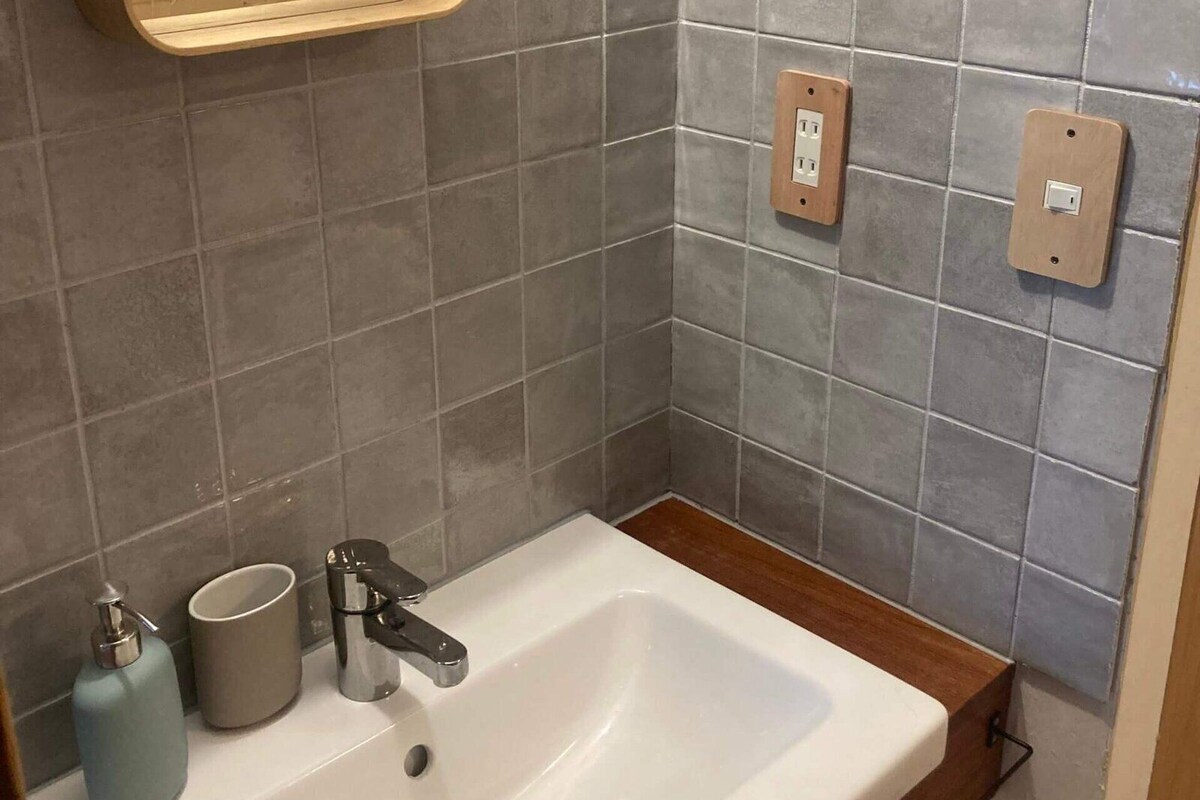 A bathroom with a white sink, a mirror, and two electrical outlets on the wall.