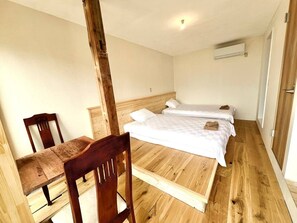 A room with two beds, a wooden chair, and a wooden table. - umi no tonari hotel & cafe (Kyotango / Tango/ Taiza)